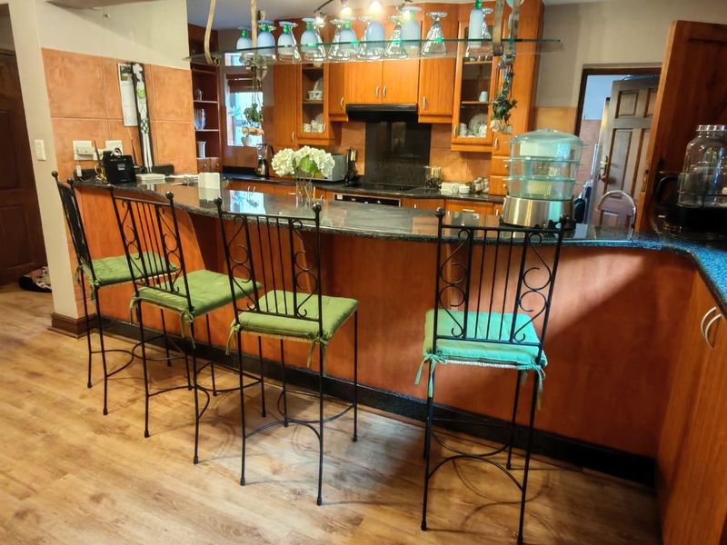 A traditional kitchen featuring wooden cabinetry, granite countertops, a breakfast bar, and a built-in hob with an extractor fan.