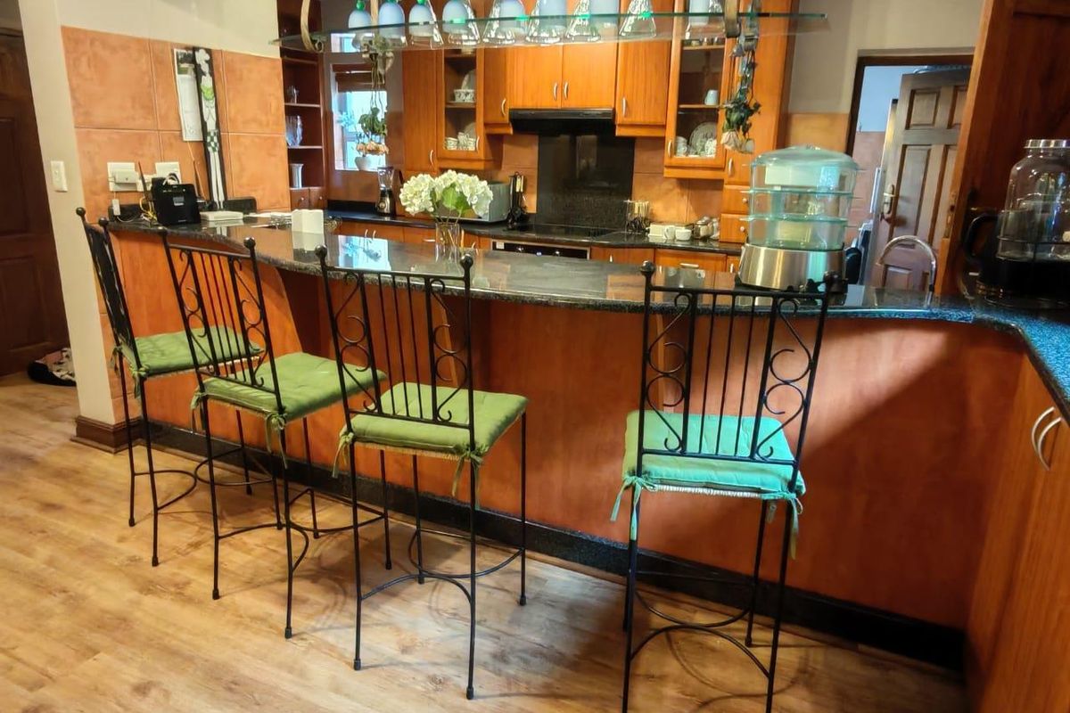 A traditional kitchen featuring wooden cabinetry, granite countertops, a breakfast bar, and a built-in hob with an extractor fan.