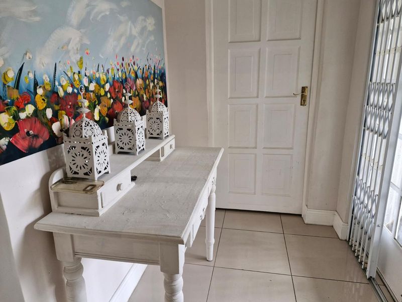 A bright entrance area featuring neutral tiled flooring, a classic panelled door, and a security gate for added peace of mind.