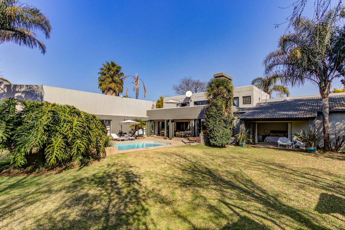 Spacious rear exterior view featuring a swimming pool, landscaped garden, and large sliding glass doors providing seamless indoor-outdoor flow.