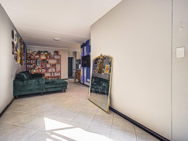 Open-plan living area featuring neutral tiled flooring and painted walls, providing a versatile space for relaxation and daily living.