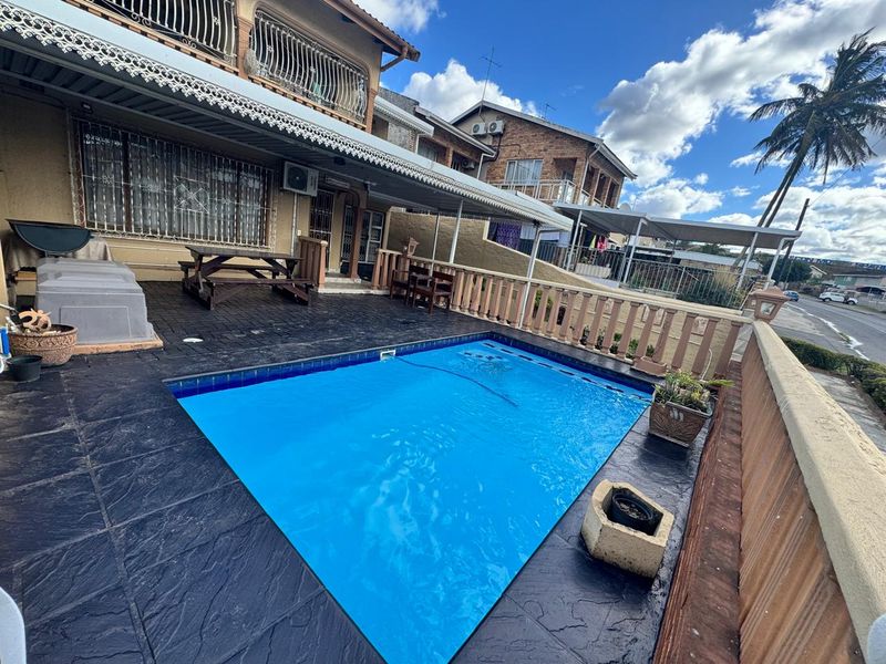 Outdoor pool area featuring a paved deck, covered patio space, and perimeter balustrade, providing a functional area for outdoor relaxation.