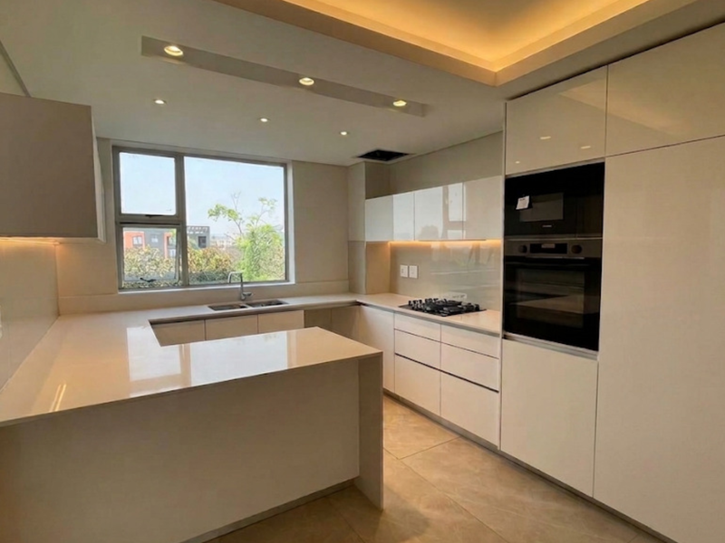 Modern, high-end kitchen featuring sleek white cabinetry, stone countertops, integrated appliances, and recessed lighting in a clean, contemporary layout.