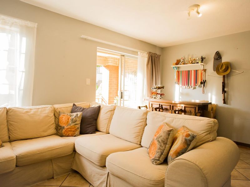 A comfortable living room featuring tiled flooring and a sliding glass door that provides access to the outdoor patio area.