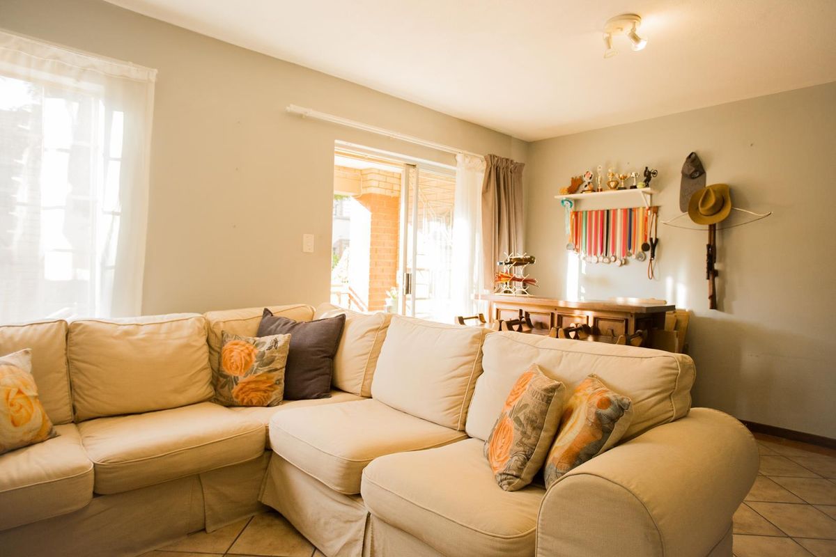 A comfortable living room featuring tiled flooring and a sliding glass door that provides access to the outdoor patio area.