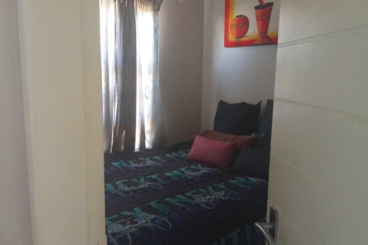 A compact bedroom featuring a window with curtains and a modern internal door.