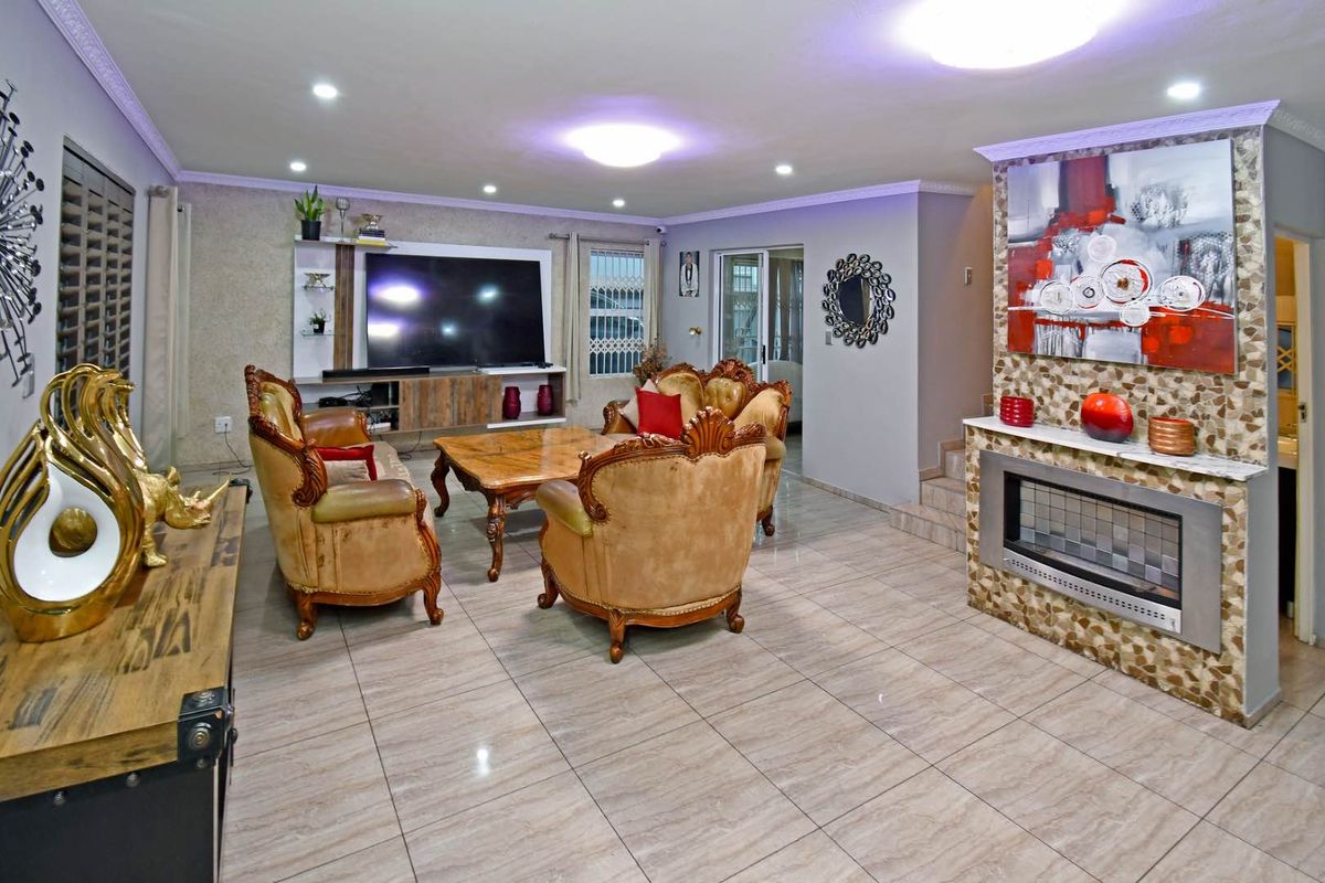 Spacious living room featuring a stone-clad fireplace, built-in media cabinetry, recessed lighting, and polished floor tiles throughout.