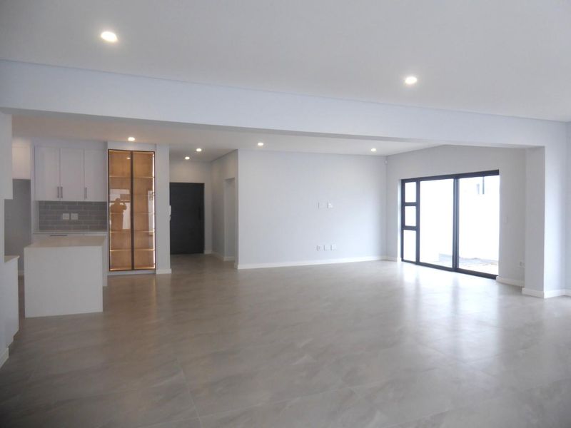 Spacious open-plan living area featuring modern tiled floors, recessed lighting, and a sleek kitchen with built-in cabinetry and a central island.