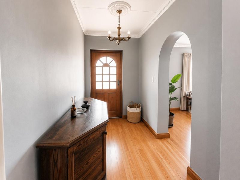 Welcoming entrance hall featuring timber flooring, a classic timber front door, and an elegant arched transition into the adjoining living space.