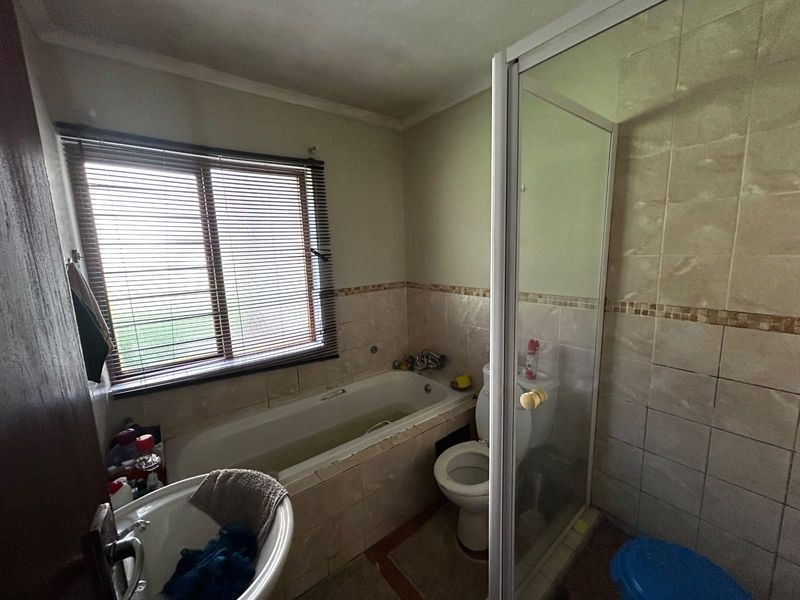 A functional bathroom featuring a built-in bathtub, separate shower enclosure, toilet, and pedestal basin with tiled wall finishes.
