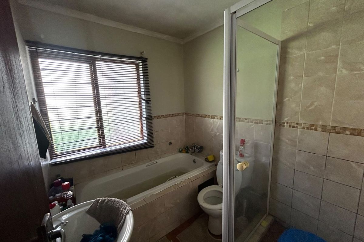 A functional bathroom featuring a built-in bathtub, separate shower enclosure, toilet, and pedestal basin with tiled wall finishes.