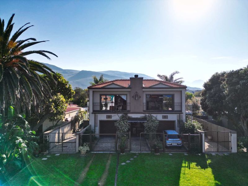 A two-story residential property featuring a terracotta tile roof, upper-level balconies with wrought iron railings, and a paved driveway with double garage access.
