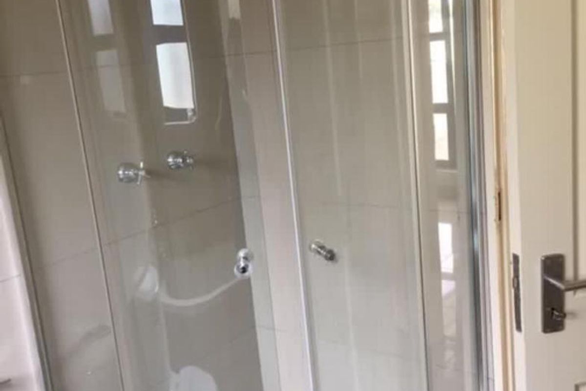 A functional bathroom shower enclosure featuring tiled walls, a glass door, and chrome fixtures.