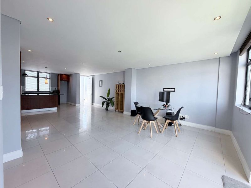 Spacious open-plan living and kitchen area featuring neutral tiled flooring, recessed lighting, and modern kitchen cabinetry with a breakfast island.