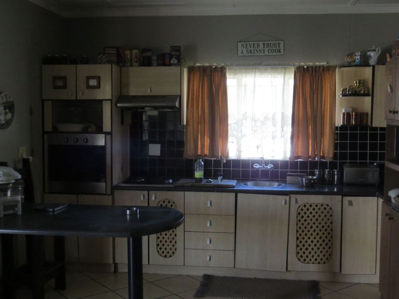 A functional kitchen featuring built-in cabinetry, integrated oven, extractor fan, and tiled backsplash with a central window for natural light.
