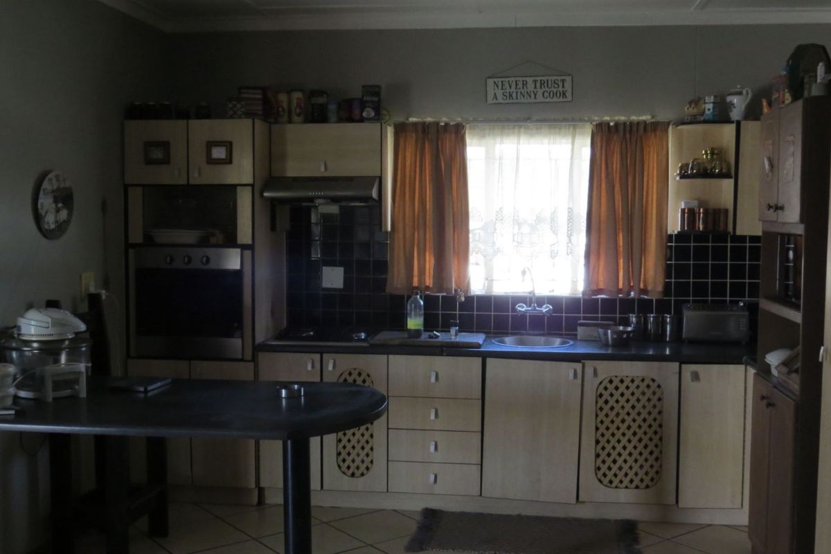 A functional kitchen featuring built-in cabinetry, integrated oven, extractor fan, and tiled backsplash with a central window for natural light.