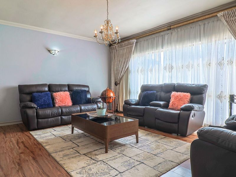 A well-maintained living room featuring laminate flooring, decorative cornice, and elegant lighting fixtures, providing a comfortable and inviting space.