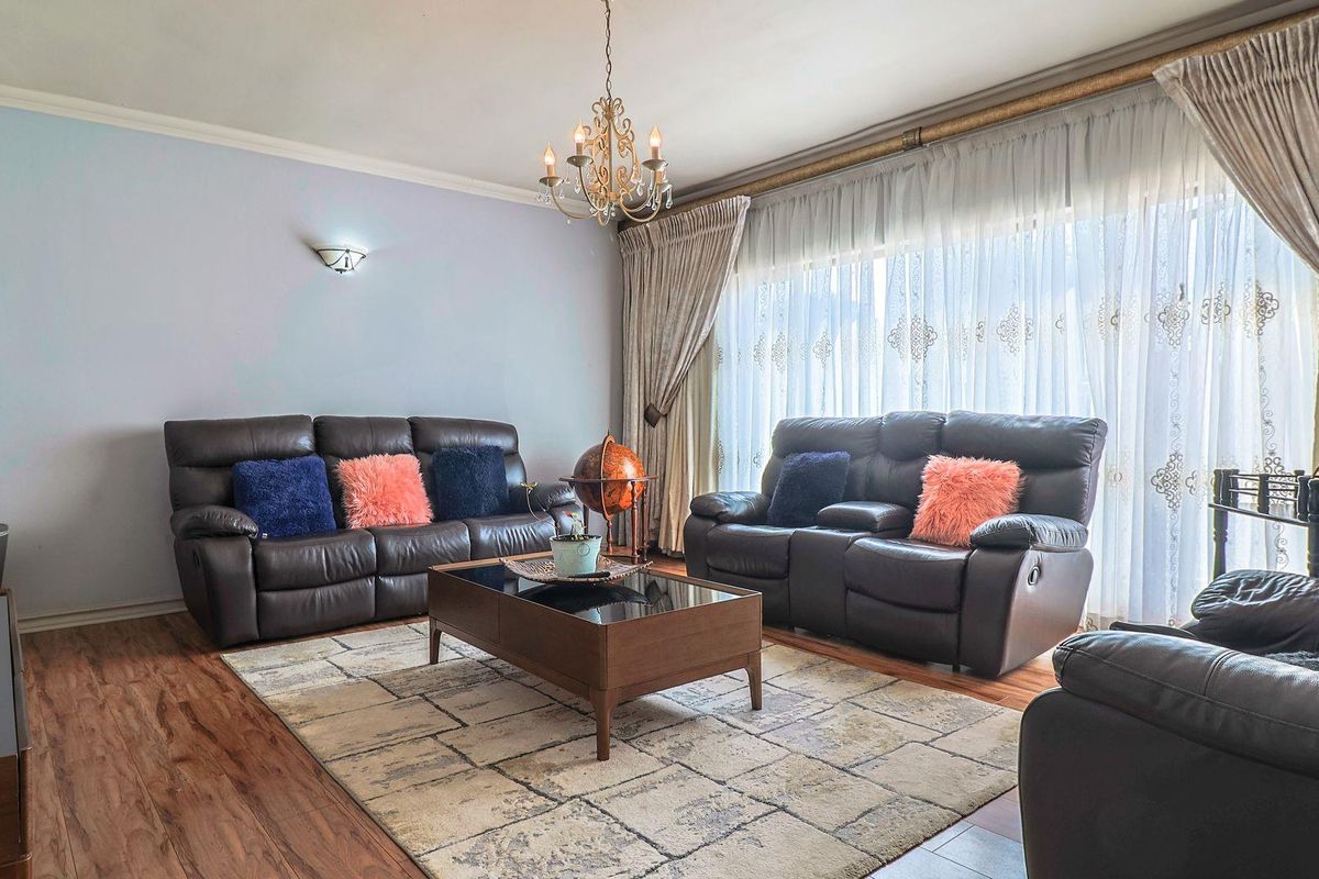 A well-maintained living room featuring laminate flooring, decorative cornice, and elegant lighting fixtures, providing a comfortable and inviting space.