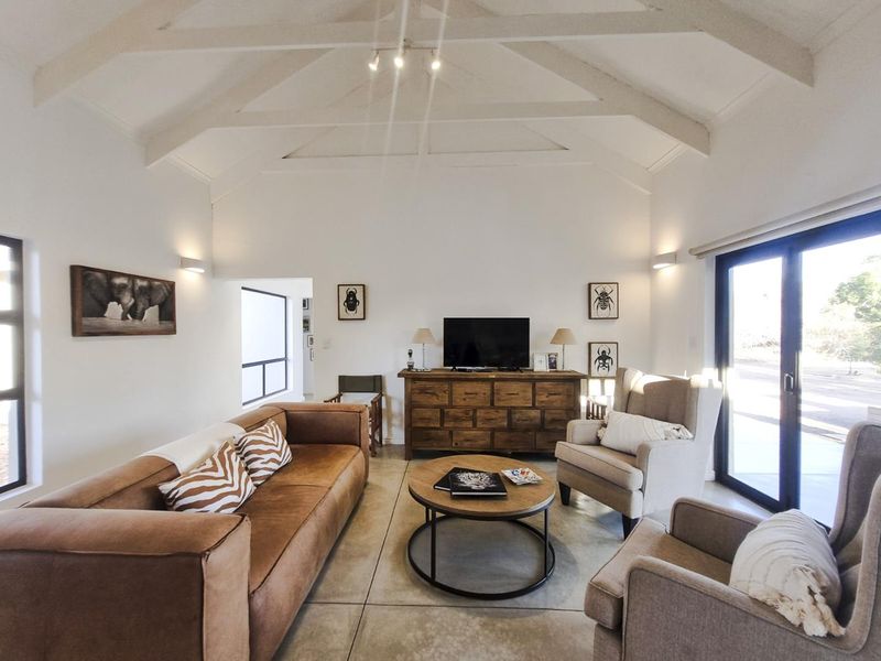 Spacious living room featuring a high vaulted ceiling with exposed beams, polished concrete floors, and large sliding glass doors providing ample natural light.