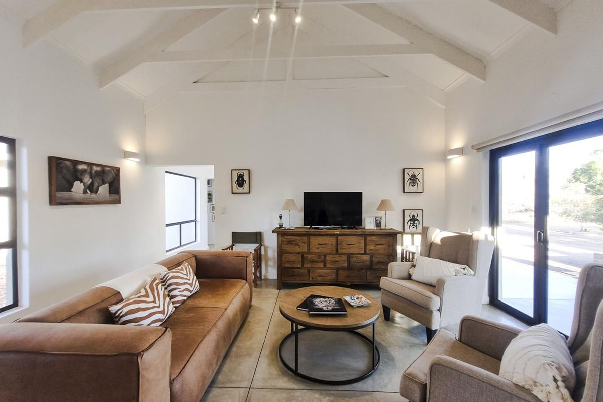 Spacious living room featuring a high vaulted ceiling with exposed beams, polished concrete floors, and large sliding glass doors providing ample natural light.