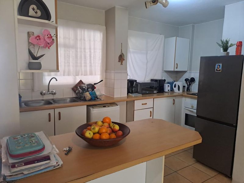 Functional kitchen featuring laminate countertops, built-in cabinetry, tiled backsplash, and a double sink, offering a practical layout for daily meal preparation.