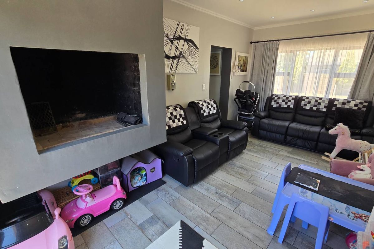 A living room featuring a large built-in fireplace, tiled flooring, and recessed ceiling lighting, offering a functional space for family living.