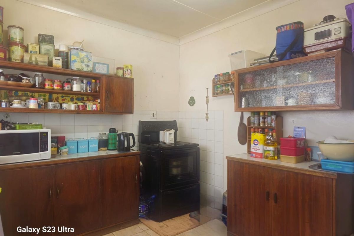 A functional kitchen featuring traditional wooden cabinetry, tiled splashbacks, and a freestanding stove, offering a classic layout with ample storage space.