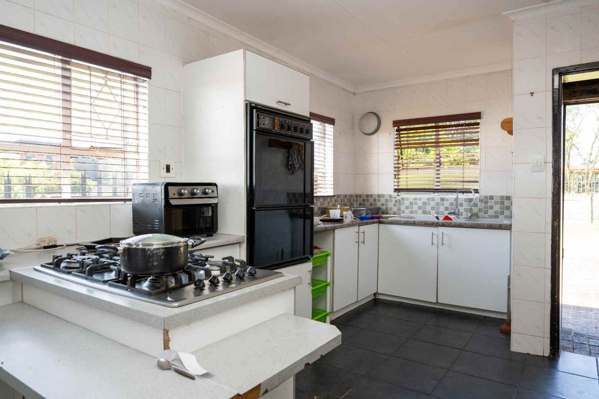 Functional kitchen featuring a gas hob, built-in oven, double sink, and ample cabinetry with tiled finishes throughout.