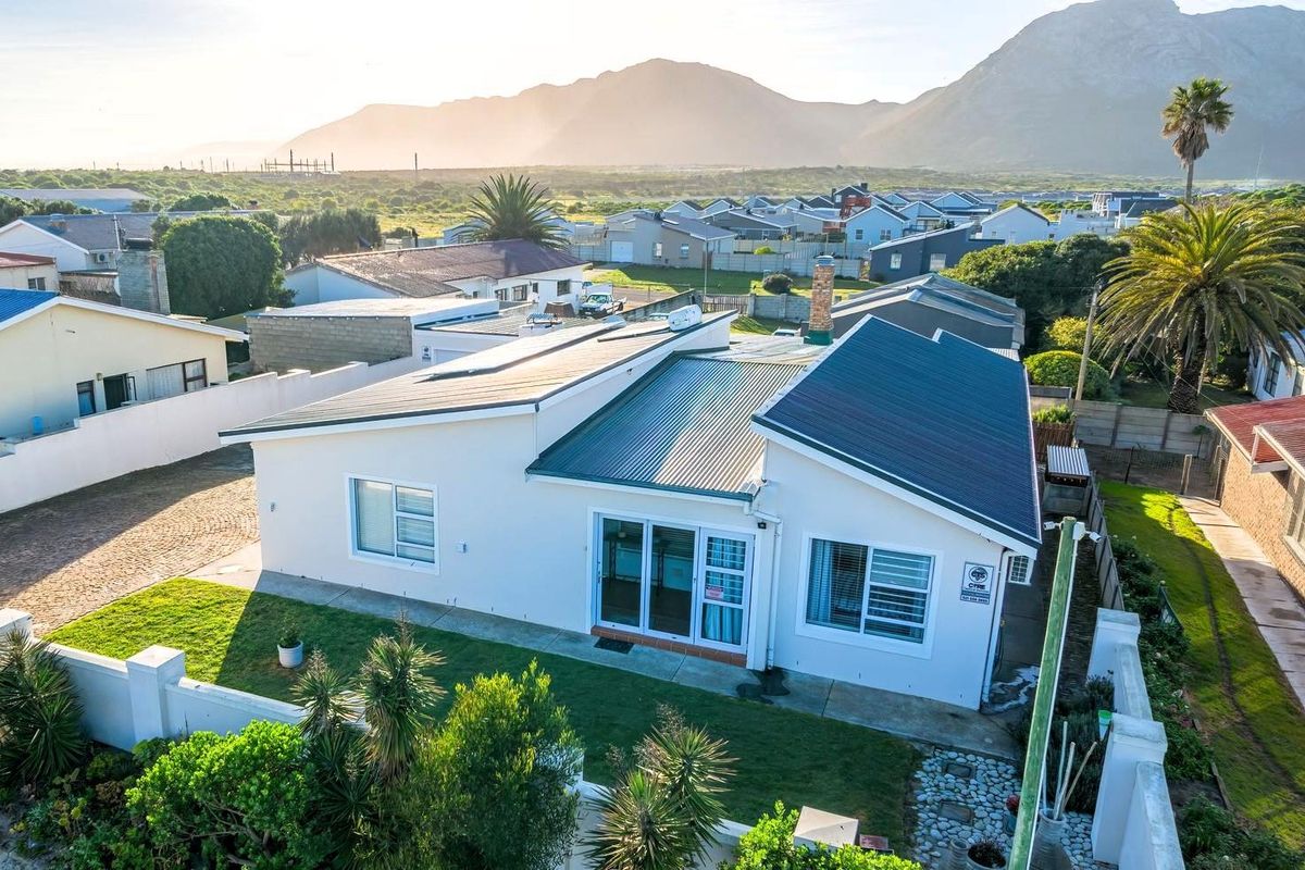 Aerial view of a well-maintained residential property featuring a modern metal roof, solar panels, and a private garden with mountain views.