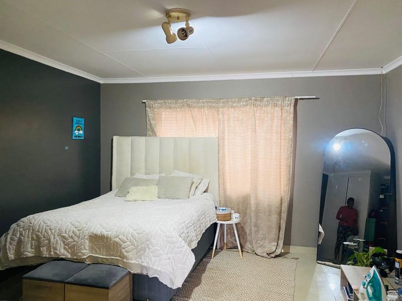 A bedroom featuring tiled flooring, neutral wall tones, and a ceiling-mounted spotlight fixture.