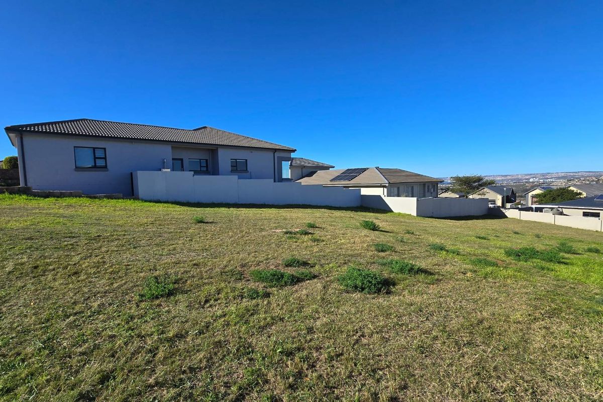 A view of a vacant residential plot featuring a gentle slope, established boundary walls, and surrounding suburban residential properties.
