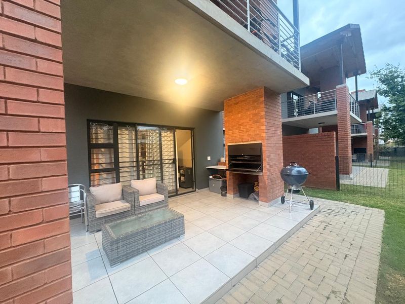 Covered patio area featuring a built-in braai, tiled flooring, and direct access to the interior through sliding glass doors.