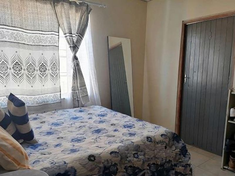A standard bedroom featuring tiled flooring and a painted timber door, providing a functional living space.