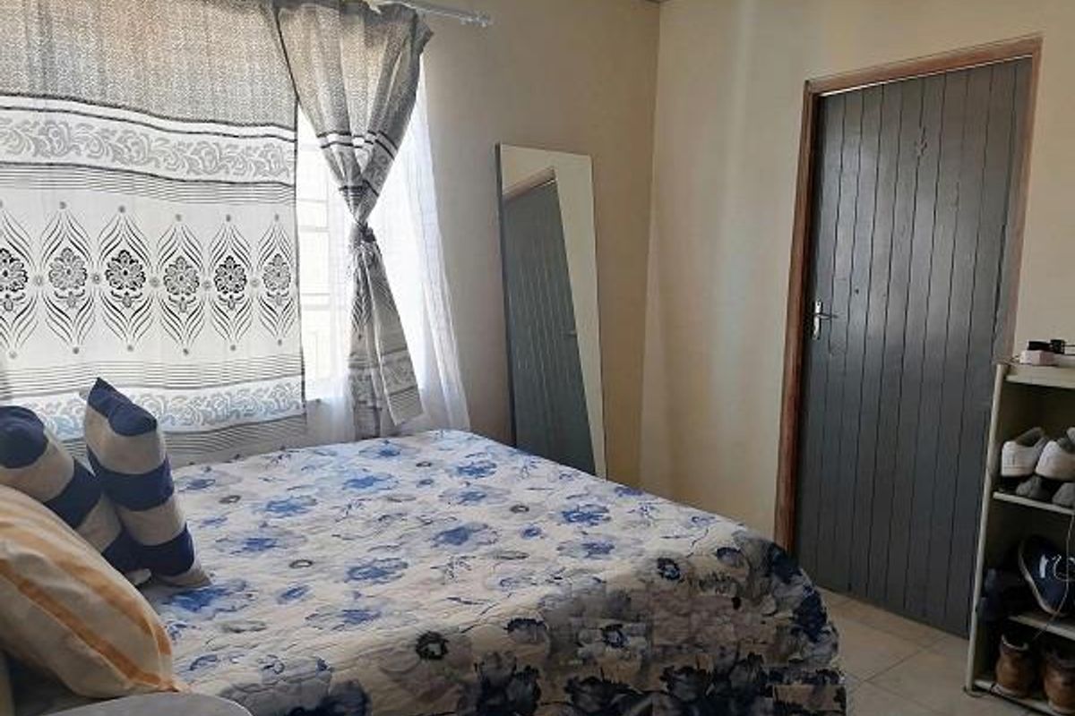 A standard bedroom featuring tiled flooring and a painted timber door, providing a functional living space.