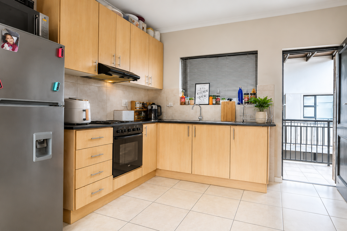 Functional kitchen featuring light wood cabinetry, built-in oven, extractor fan, and tiled flooring, with direct access to an outdoor balcony area.