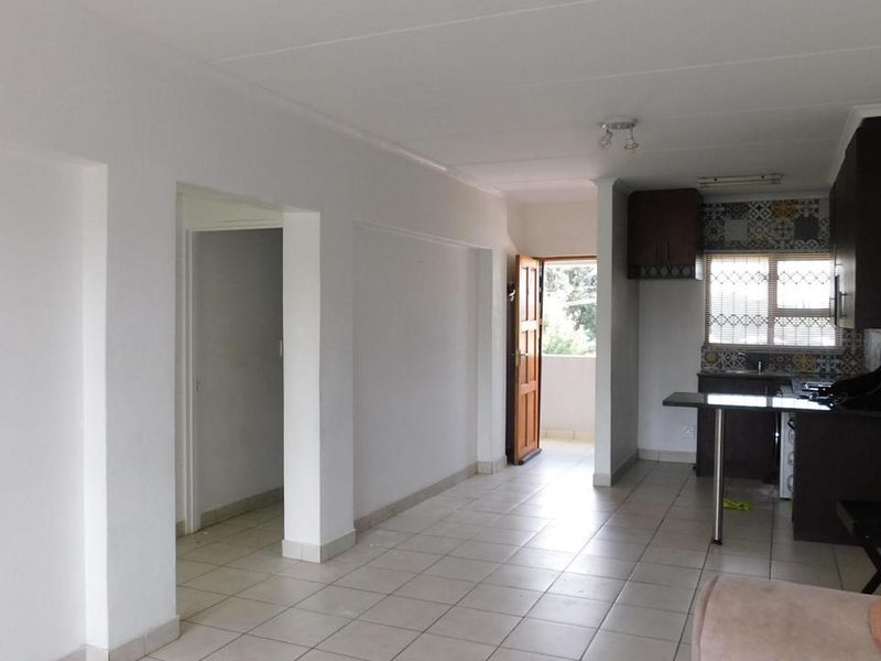 Open plan living area featuring tiled flooring and a functional kitchen with built-in cabinetry and a breakfast bar.