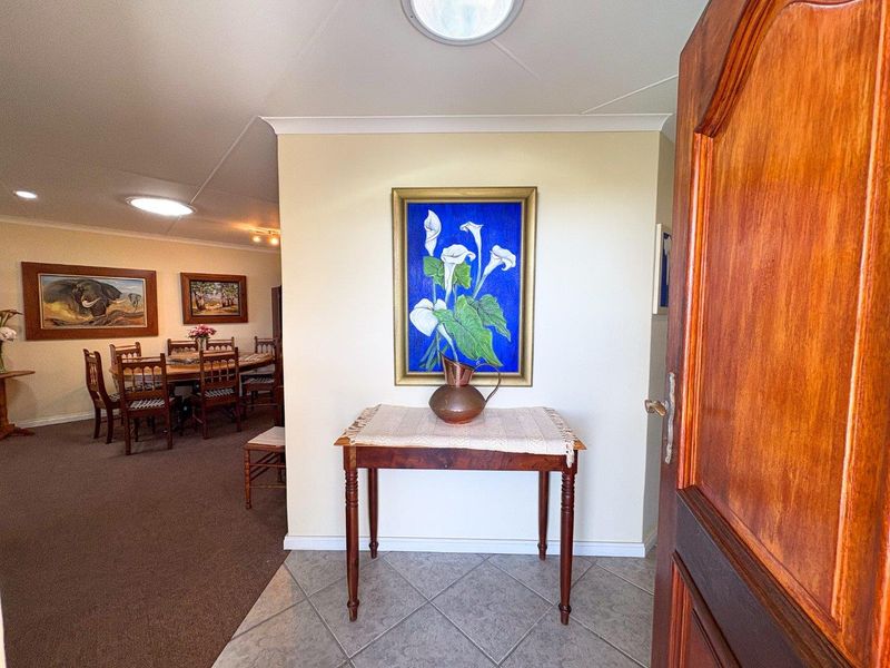 Welcoming entrance foyer featuring tiled flooring and a solid timber front door, leading into an open-plan living and dining area.