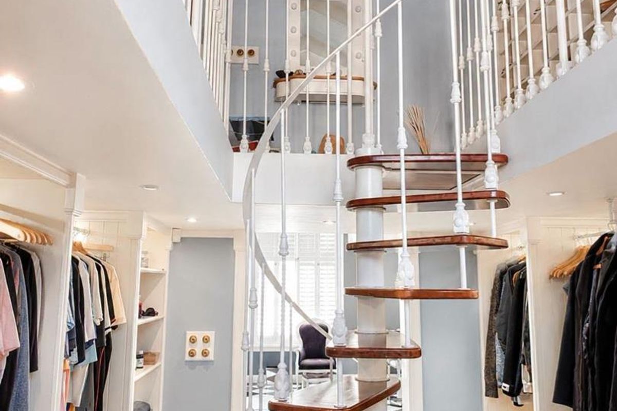 A stylish dressing room featuring a central spiral staircase, built-in wardrobe cabinetry, and classic checkered tile flooring leading to a mezzanine level.