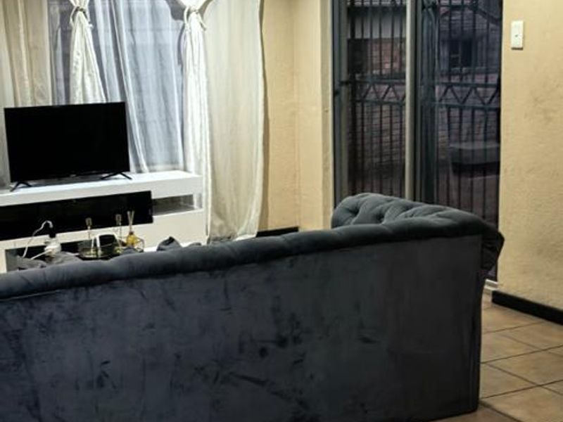 A living room featuring tiled flooring, recessed lighting, and a sliding glass door providing access to the exterior.