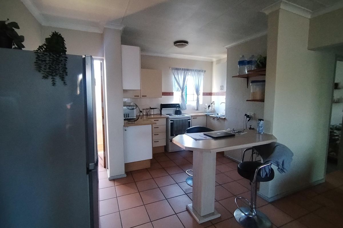 Functional kitchen featuring tiled flooring, built-in cabinetry, a breakfast bar, and a freestanding stove, offering a practical layout for daily meal preparation.