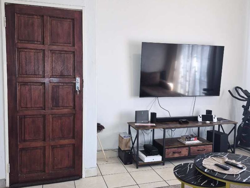A living room area featuring tiled flooring and a traditional dark timber panel door.