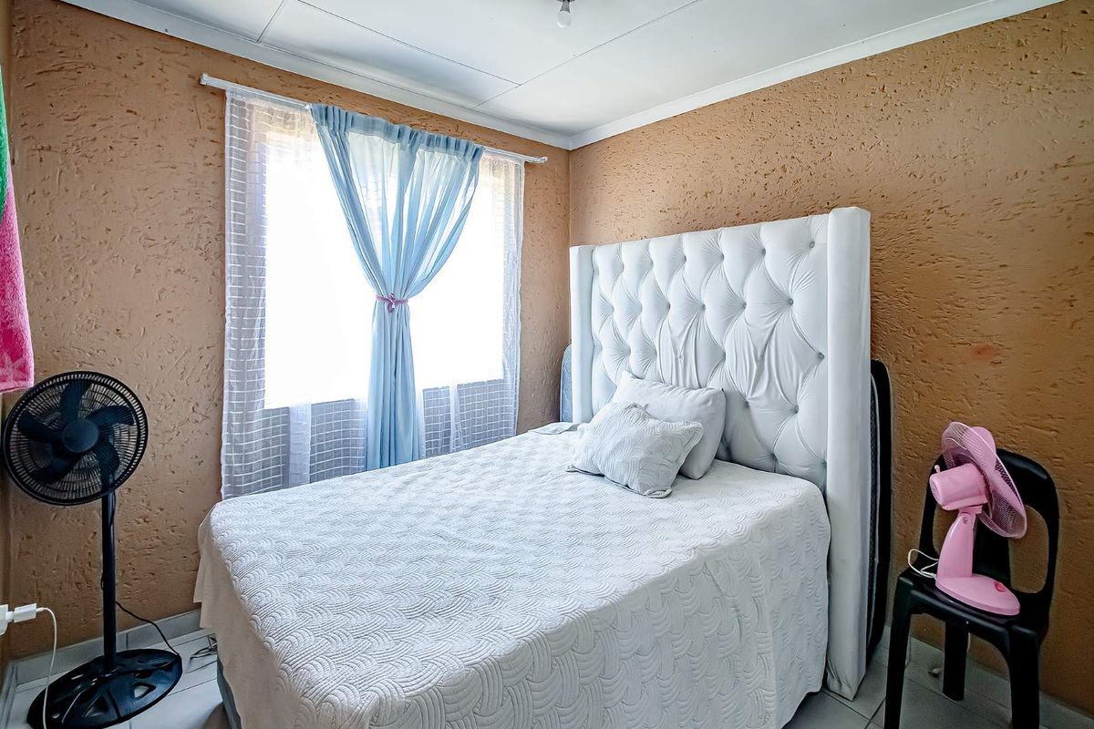 A bedroom featuring textured walls, tiled flooring, and a coved ceiling, offering a functional space ready for cosmetic updates.