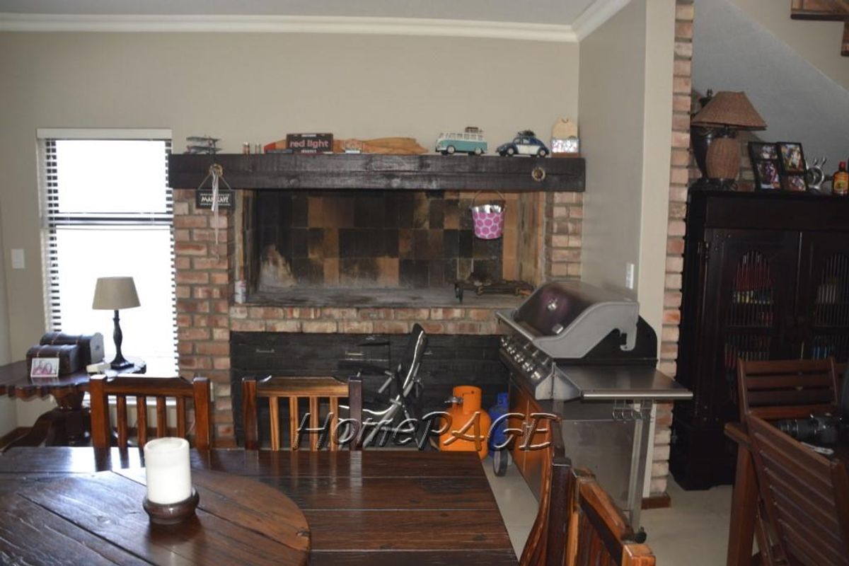 Indoor entertainment area featuring a large built-in brick fireplace with a dark timber mantle and tiled hearth.