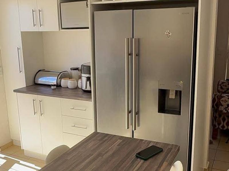 A functional kitchen area featuring white built-in cabinetry, wood-look laminate countertops, a dedicated wine rack, and tiled flooring.