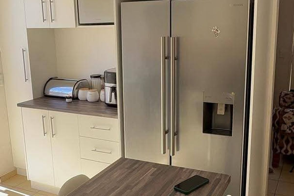 A functional kitchen area featuring white built-in cabinetry, wood-look laminate countertops, a dedicated wine rack, and tiled flooring.