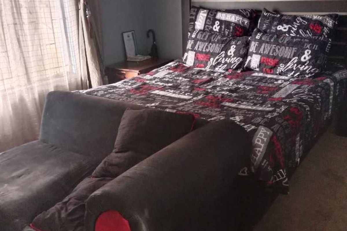 A bedroom featuring a built-in headboard and window with curtains.