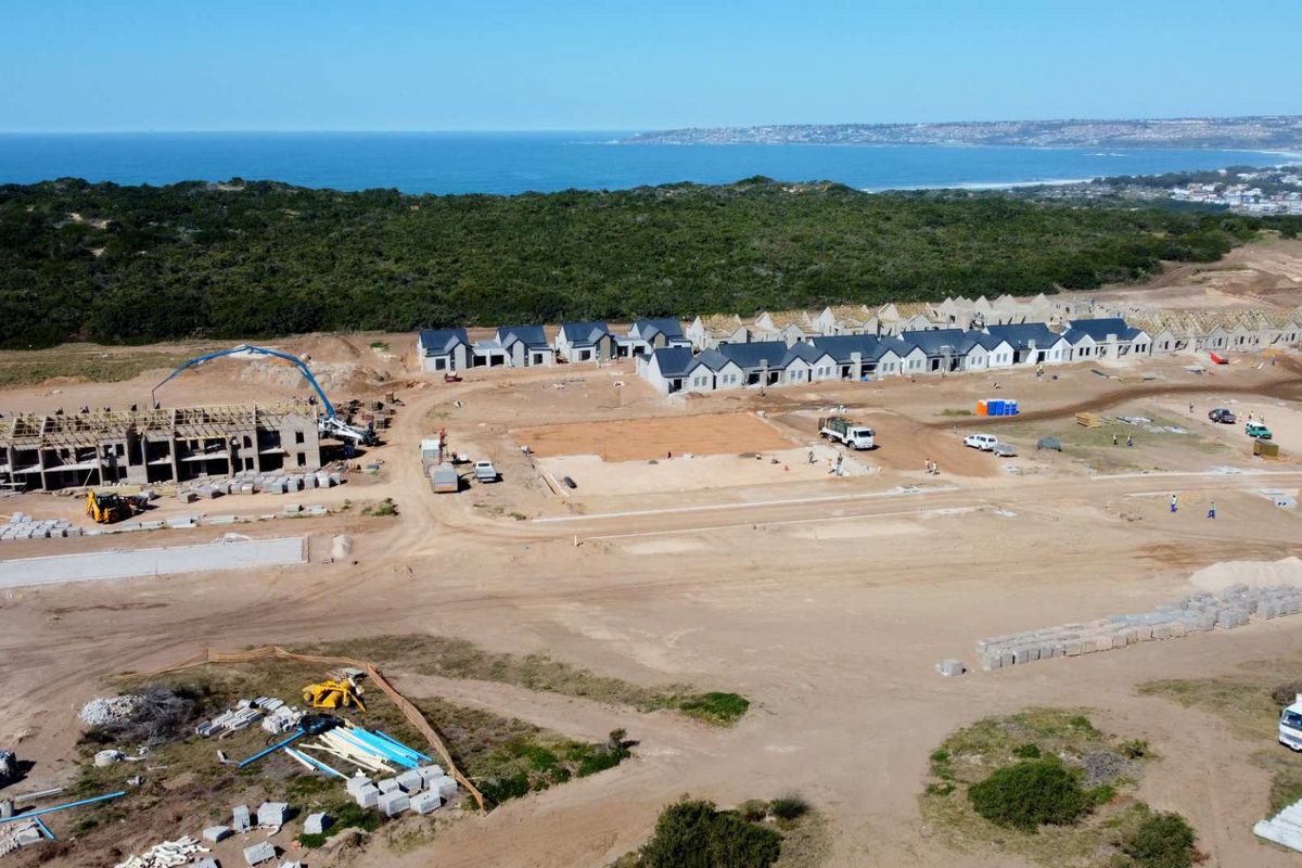 Aerial view of a residential development site under construction, featuring multiple building structures in progress and coastal landscape views.
