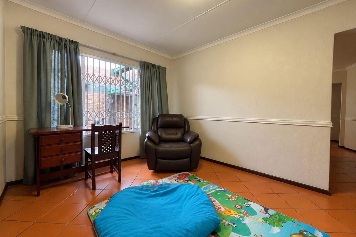 A bedroom featuring tiled flooring, security bars on the window, and decorative chair rail molding.