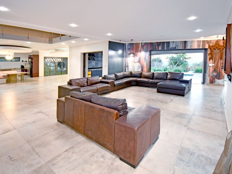 Spacious open-plan living area featuring large format floor tiles, recessed lighting, and seamless access to the outdoor pool area through wide sliding glass doors.