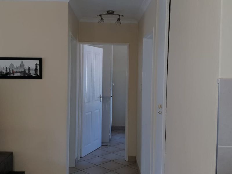 A functional hallway connecting interior spaces, featuring tiled flooring and neutral wall finishes, providing access to adjacent rooms through standard internal doors.